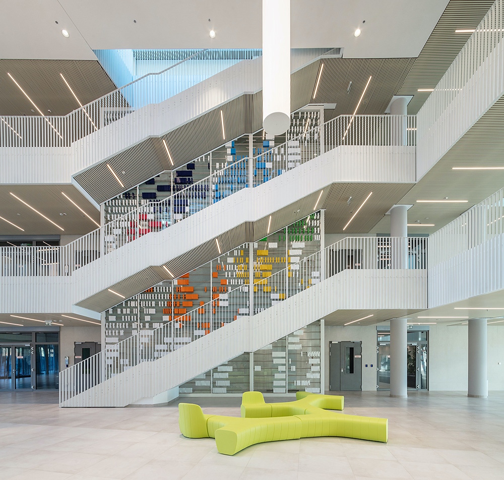 Az aula amorf, szerteágazó szárakkal játszó ülőrendszerei, mint színes objektek egy-egy ponton valósággal felpezsdítik  a belső teret