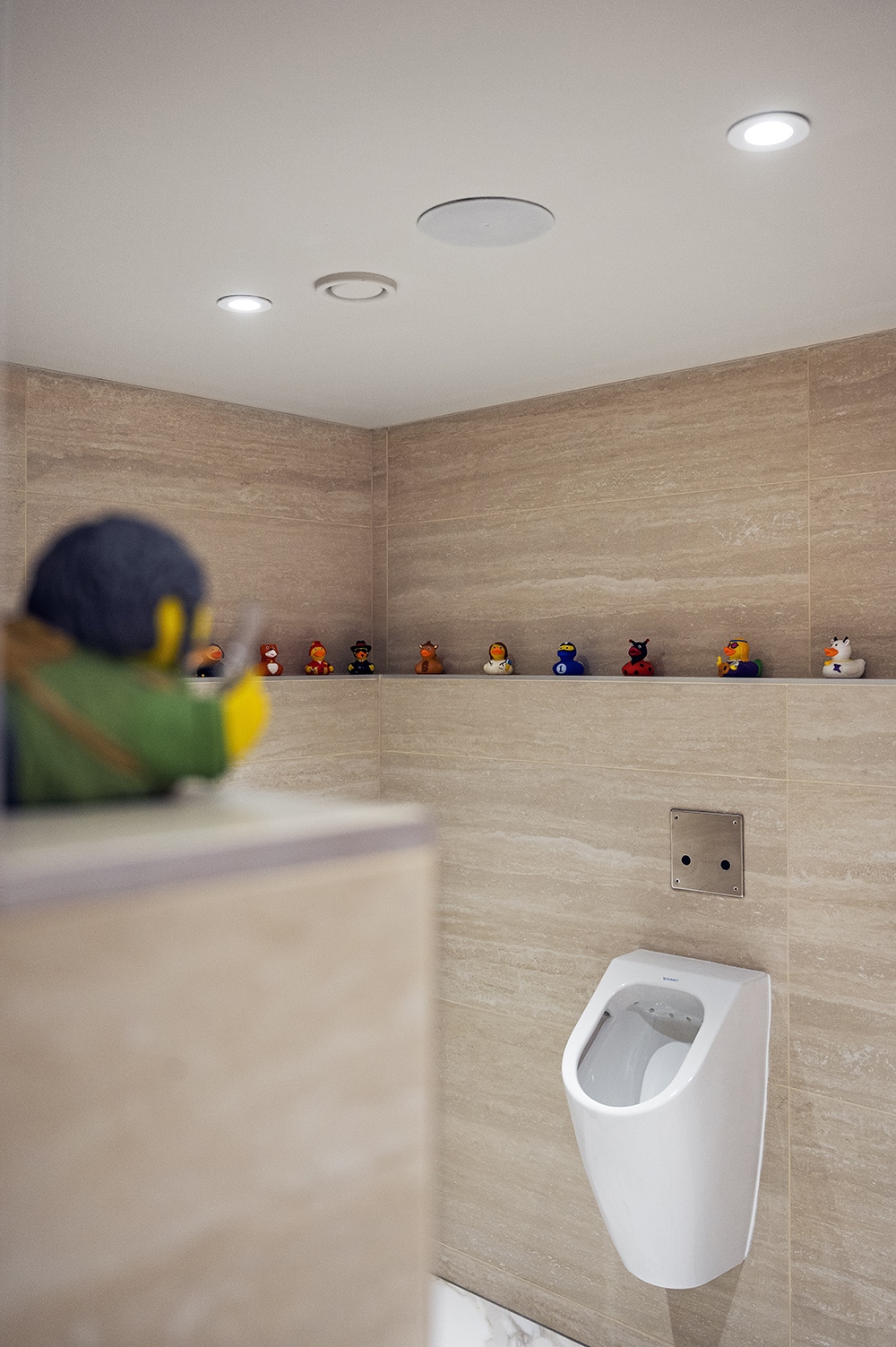 A műalkotások mellett olyan gegek is megjelennek, mint a férfi mosdóban látható fürdőkacsa-kiállítás