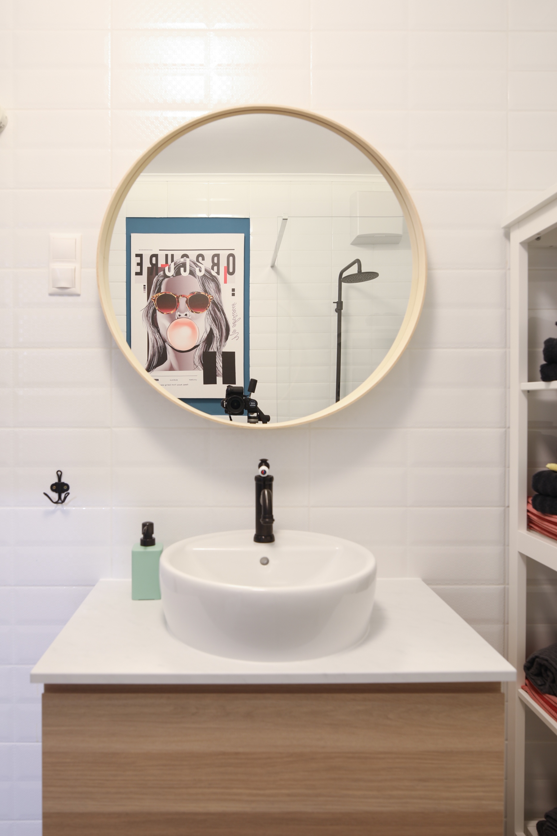 A lágyan ívelt gömbölyded mosdóhoz jól illik az egyszerű és letisztult, kör alakú fali tükör a fürdőszobában, ahol a fiatalos stílust mindössze egy vagány kép jeleníti meg a falon.