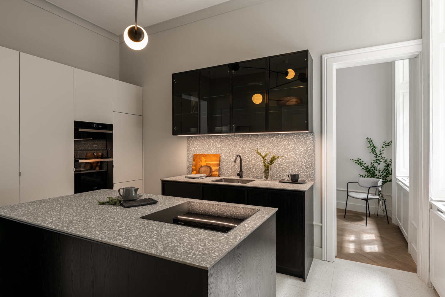 A konyhabútor három különálló elemből áll, amiket a világítás mellett a hidegburkolat és a terrazzo konyhapultok játékos felülete fog össze.