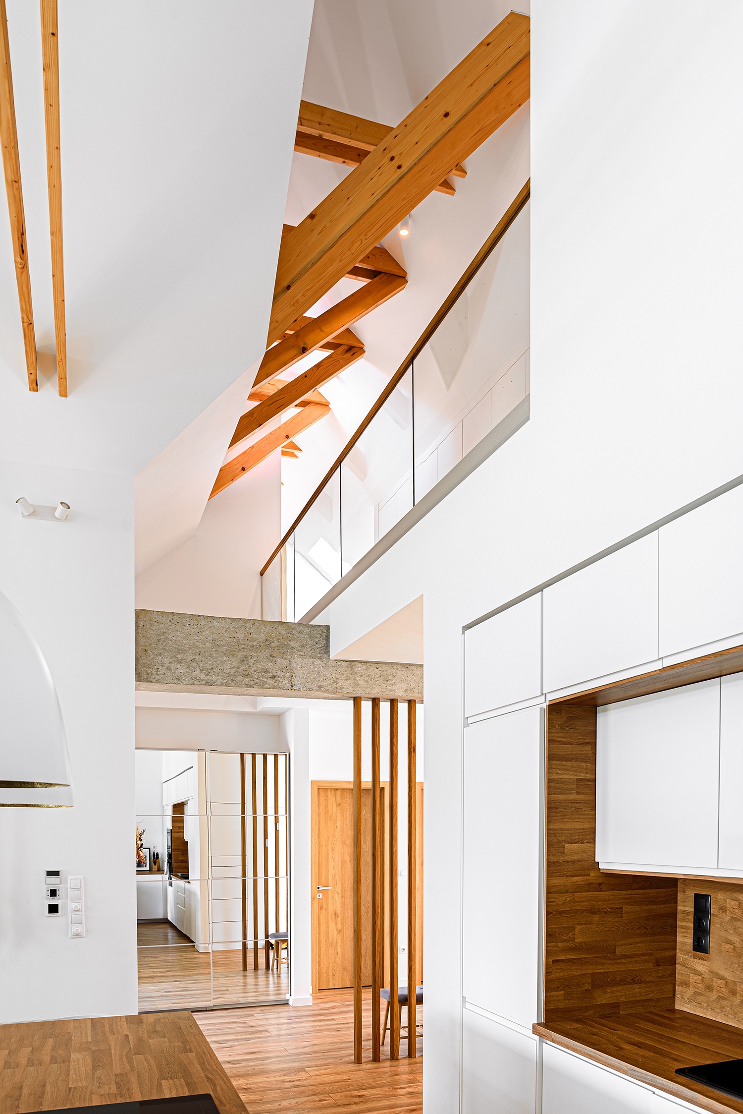 A tágas közösségi tér a konyhát, a nappalit és az étkezőt egyesíti, a látszó fedélszékes nagy belmagasság az emeleti galériával is vizuális kapcsolatot teremt