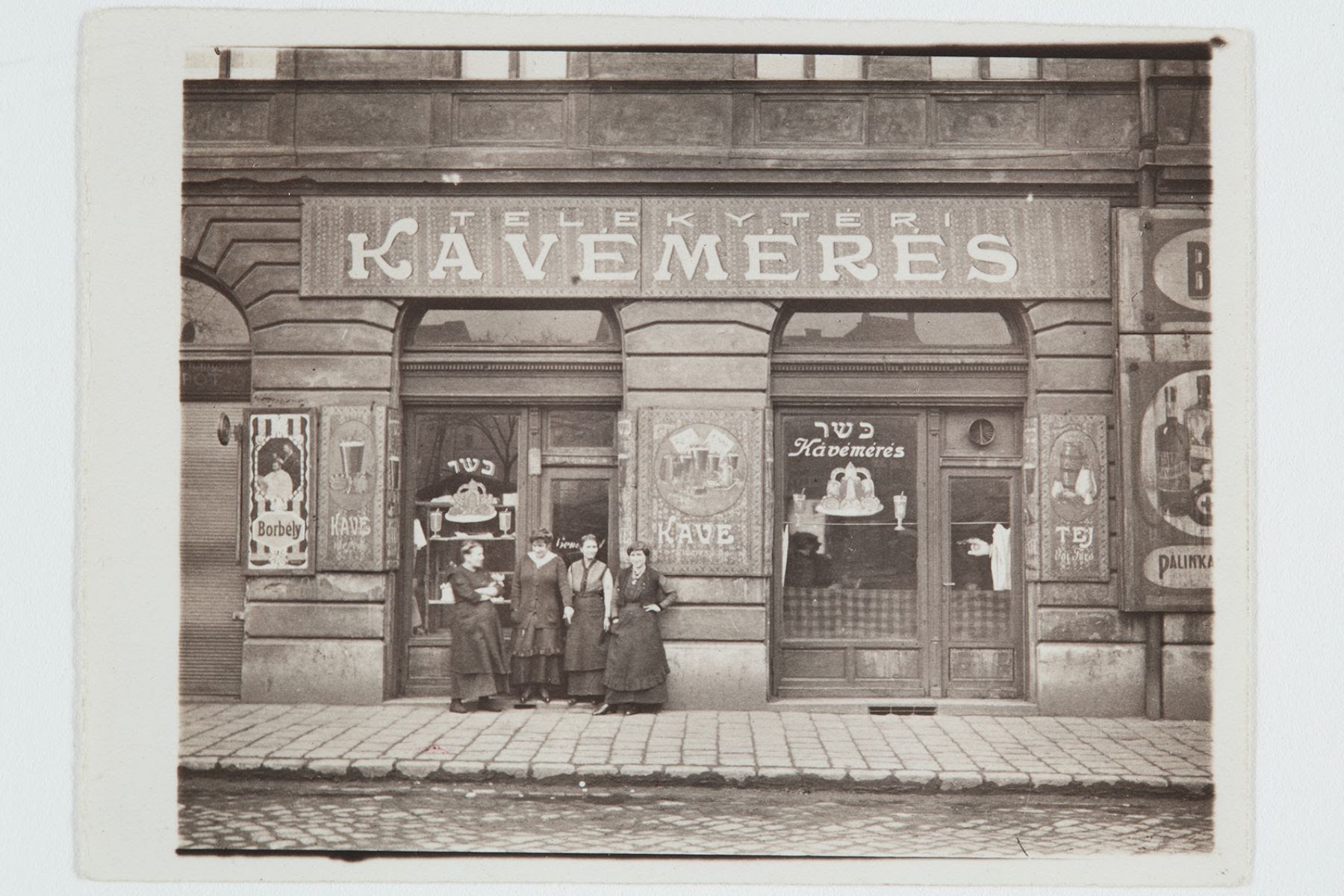 Kertész anyjának kávémérése, Budapest, Teleki tér, 1910-es évek. (A csoport bal oldalán Kertész édesanyja.) © Estate of André Kertész, Magyar Nemzeti