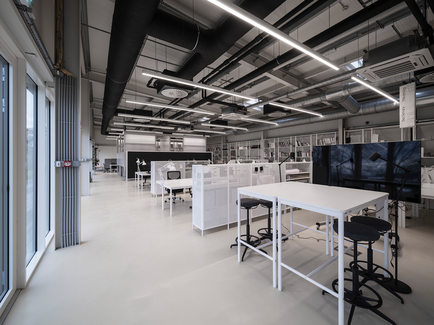 Az irodában és az oktatási térben a látszó gépész indusztriális dizájnt ad a feketefehér csarnoktömegnek