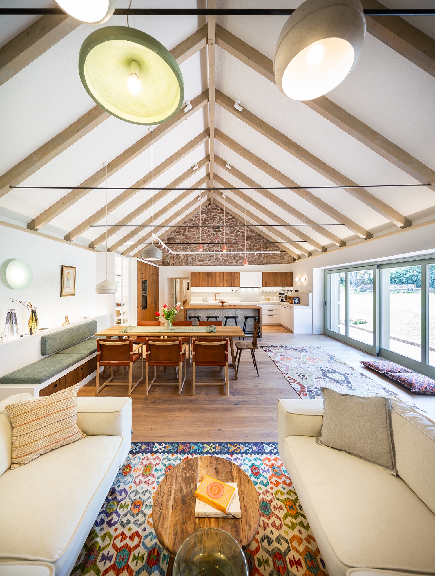 A főzési-étkezési funkció átkerült a korábban talán raktárnak vagy állatok tartására használt, de már az első átalakításkor önálló lakrésszé alakított, tágas helyiségbe, kiegészülve nappali és kényelmes étkező funkcióval, hatalmas, látványos fényáradatot biztosító üvegfelülettel