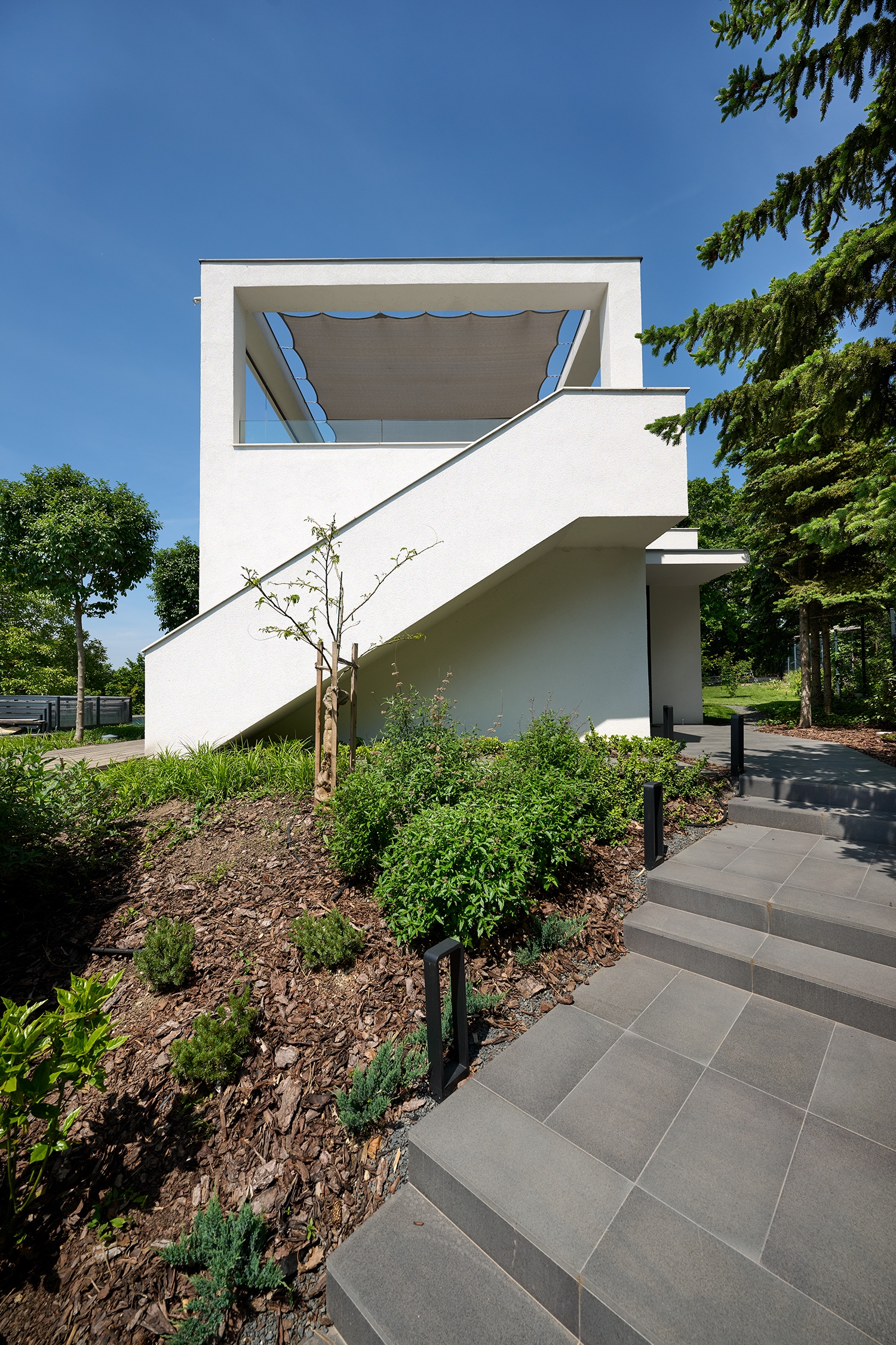 Mivel az emelet lett a közösségi terek helyszíne, a fenti teraszt a medence felől is meg lehet közelíteni egy nagyobb lépcsőn át