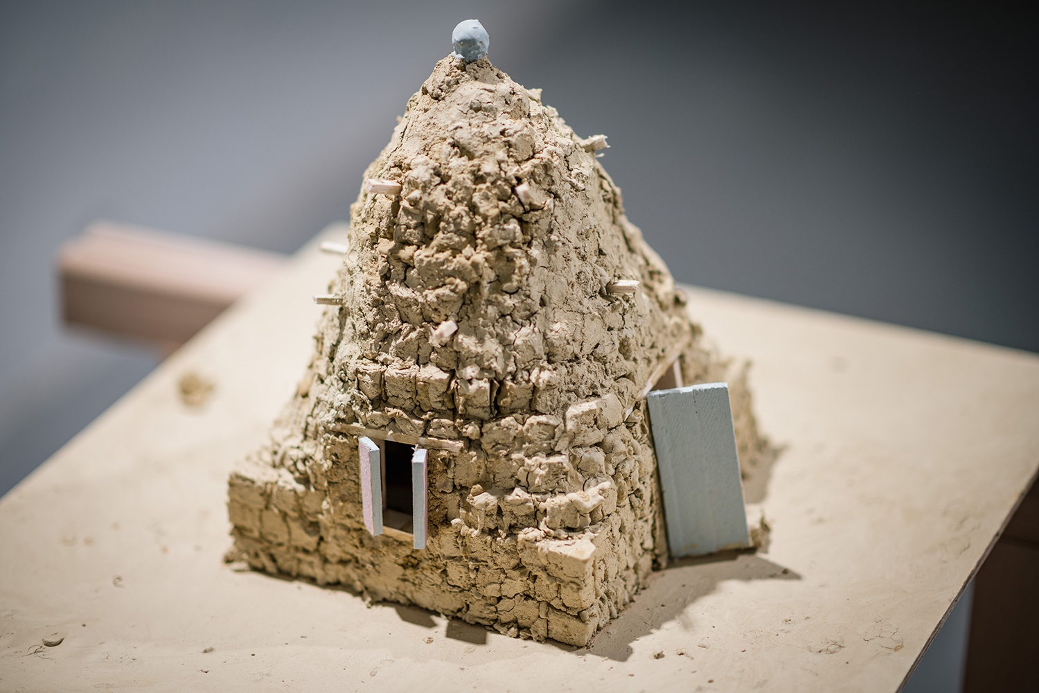 A felépített ház-installáció mellett, a szír vályogházak makett formájában jelennek meg.