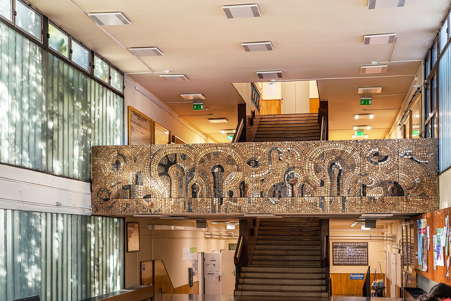 A hosszan előrenyúló, közösségi tereket is rejtő épület lépcsőházának mellvédjét Szabados János mozaikja díszíti.