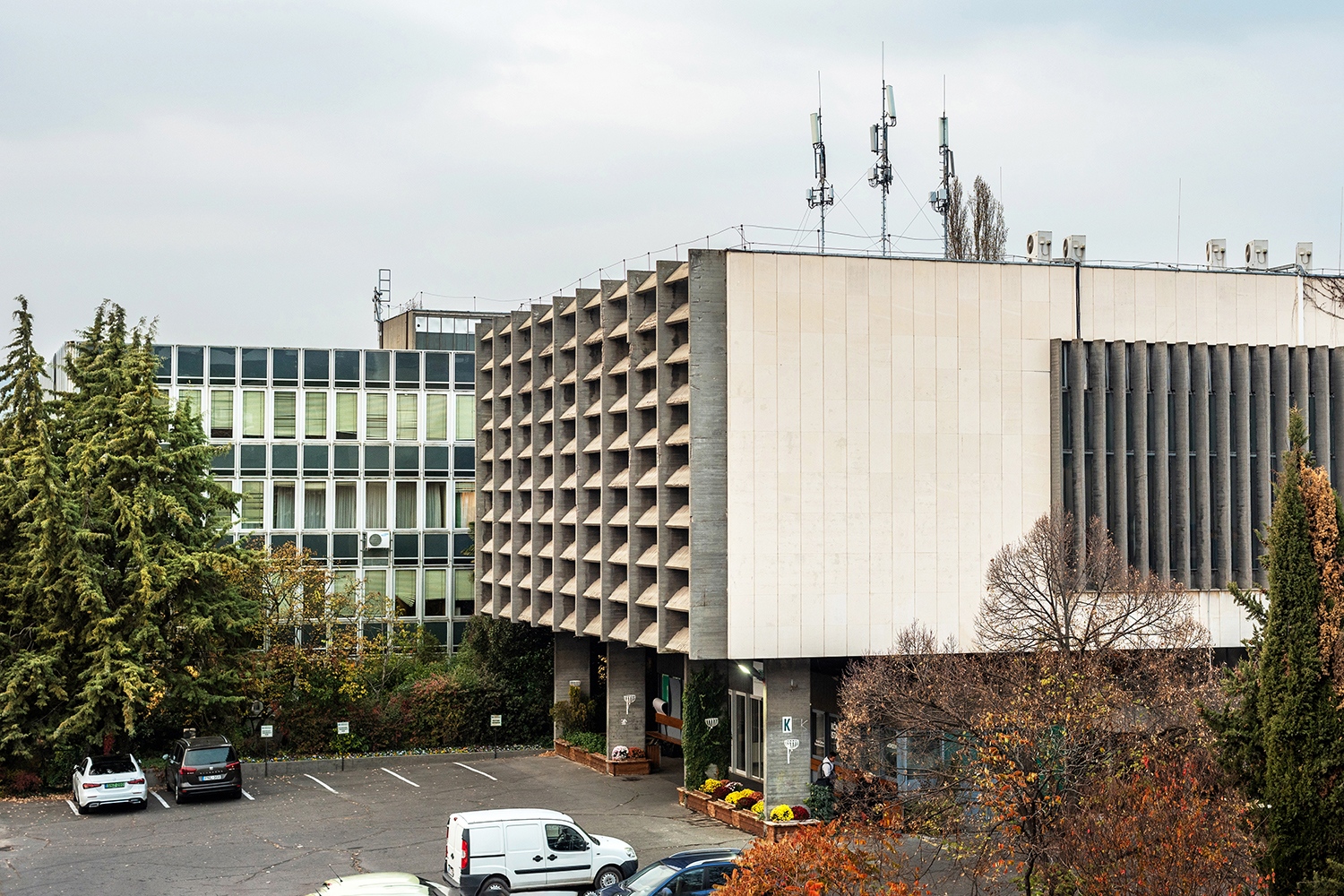 A nyaktaggal összekapcsolt két épületrész közül a kisebbik, alumínium függönyfalas szárnyban helyezték el az adminisztratív helyiségeket, irodákat, míg a lejtős terepbe hosszan benyúló másik egység rejti a közösségi helyiségeket, a nagyelőadókat, a könyvtárat, valamint az aulát.