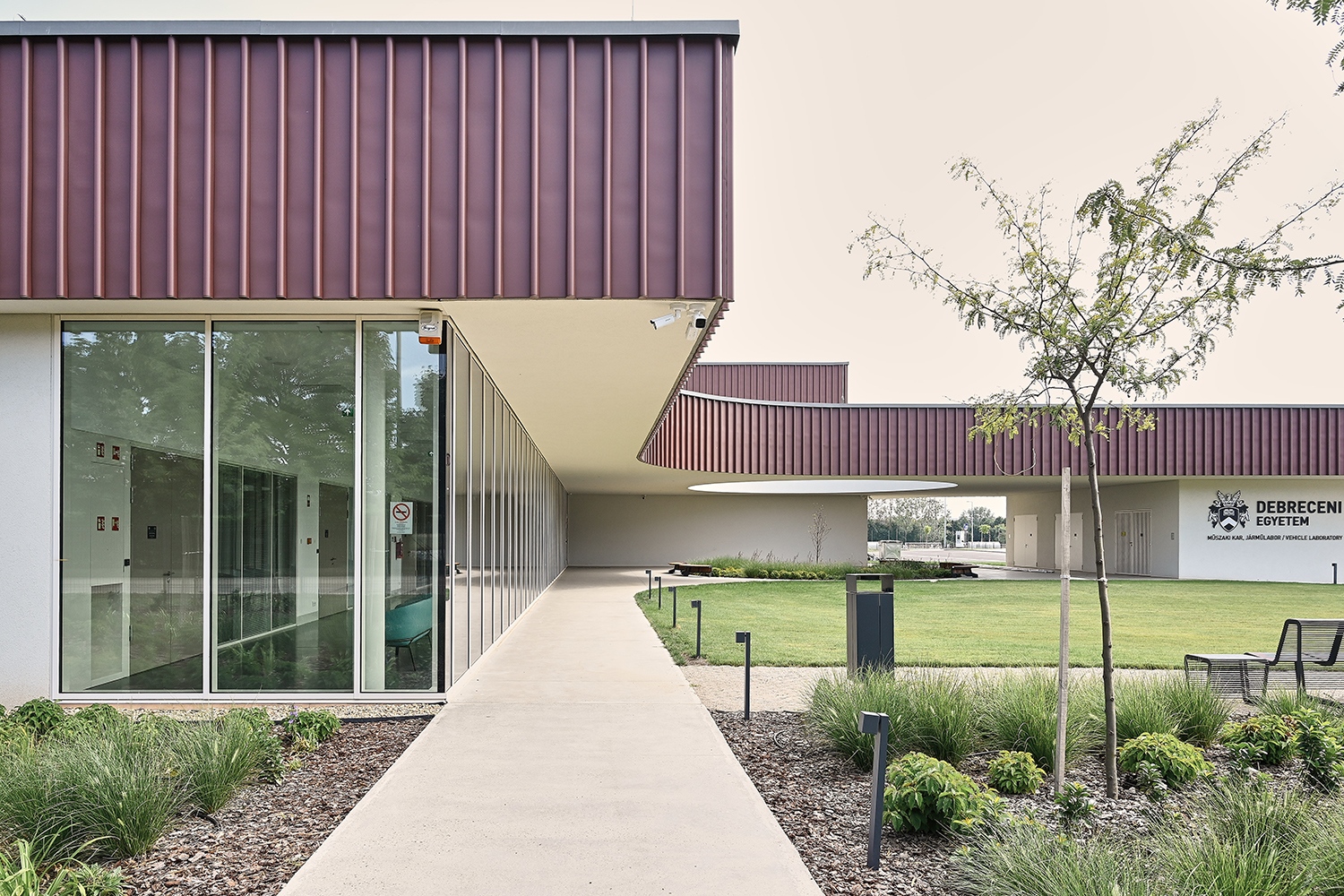 Az egységesen nemes anyaggal, bordázott cinklemezzel burkolt, lendületesen megformált előtető széles karimájú kalapként borul a tagolt tömegre, egyedi arculatot kölcsönöz az amúgy egyszerű, funkcionális épületnek