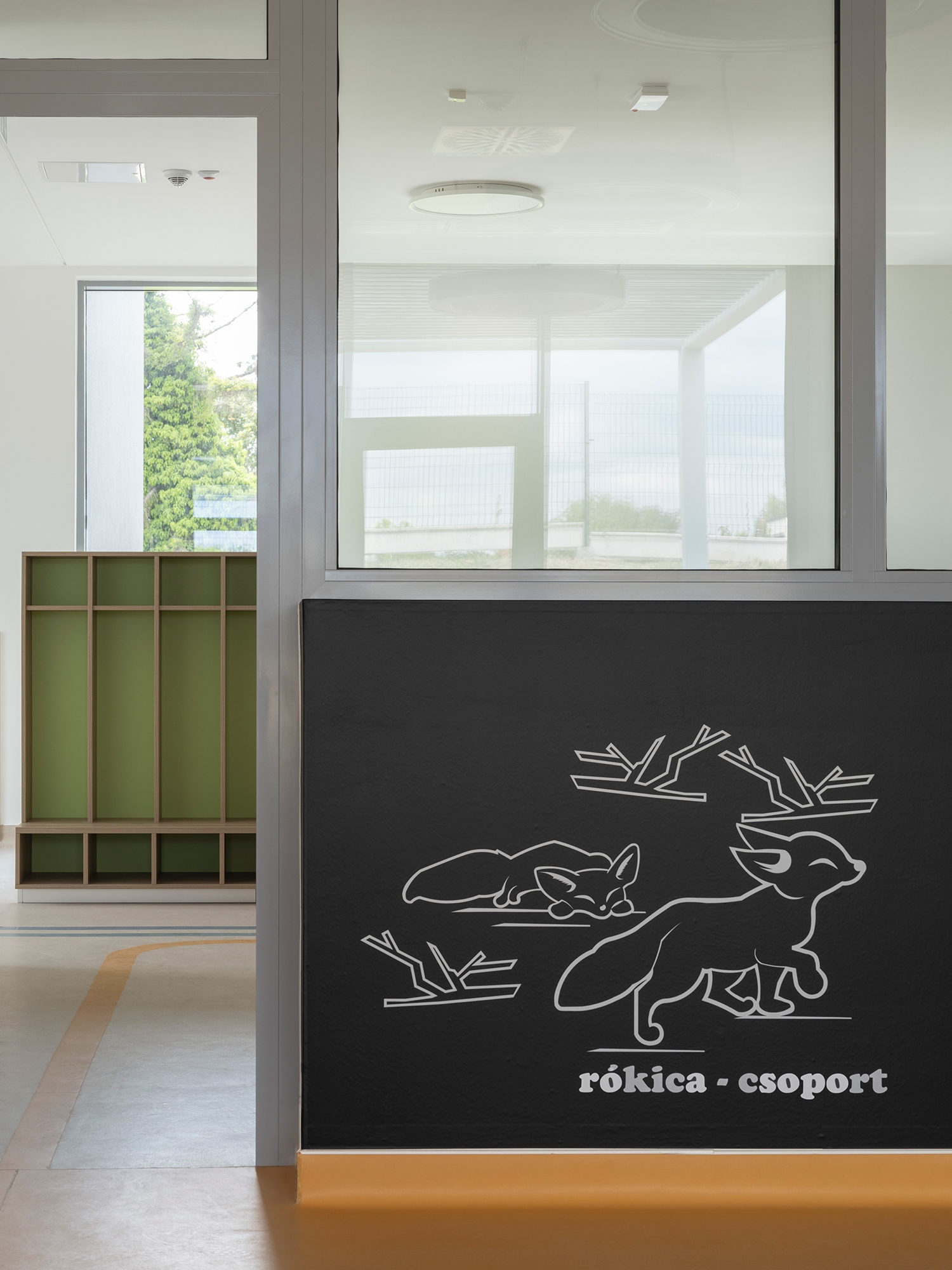 Már az aulából indulva a linóleum sávjának színe segíti az ovisok csoportba jutását. A minden színhez csoport nevét adó állatfigura is kapcsolódik.