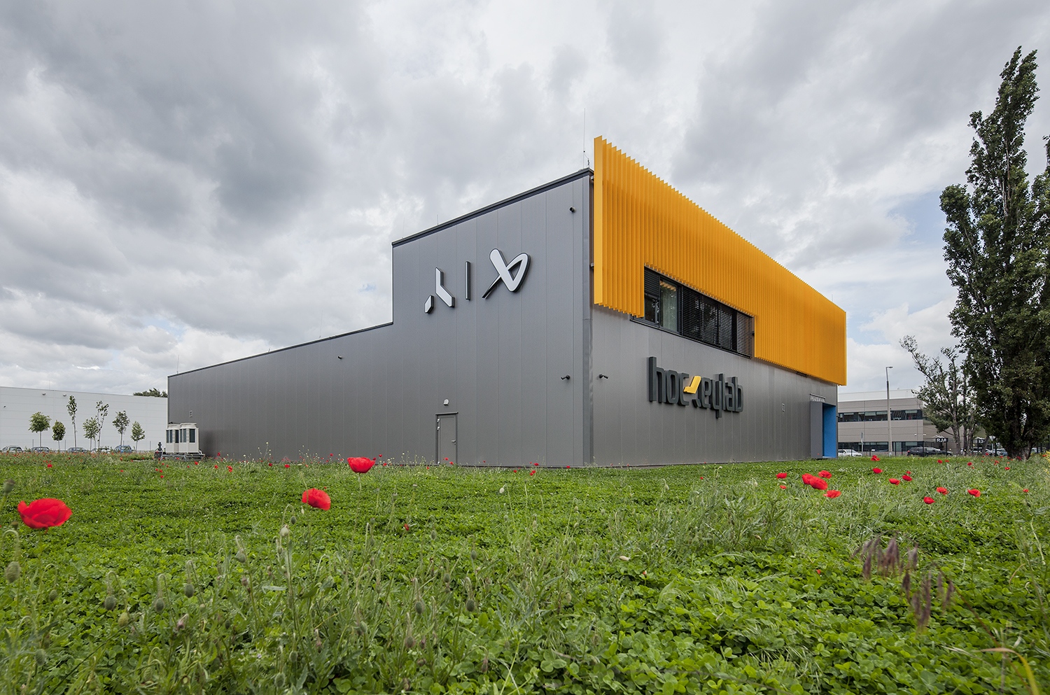 Az ipari övezetet idéző – egyszerű és olcsó – szendvicspanel-burkolat a szokottnál sokkal finomabb részletekkel: rejtett rögzítéssel, álló kivitelben készült