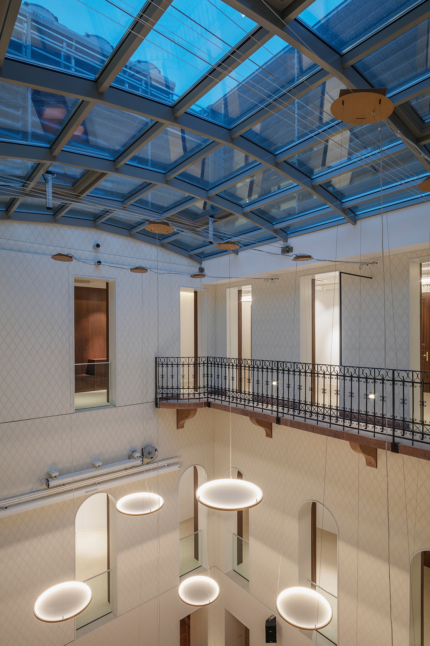 Az üveggel fedett udvar belsőépítészeti kialakítása kortárs hangon ugyanazt a míves minőséget közvetíti, mint a 19. század részletképzése